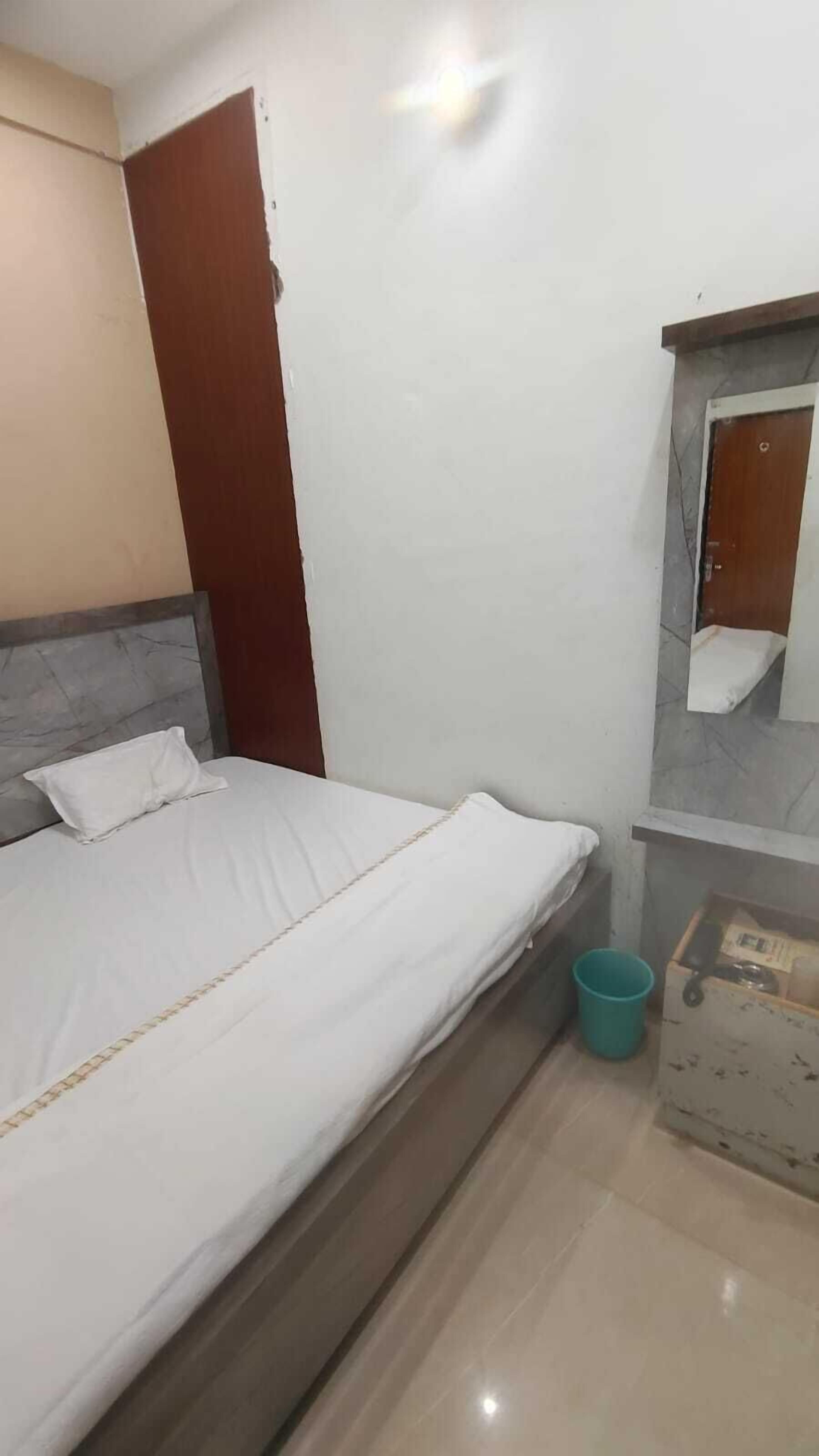 A bedroom with a bed, a wooden headboard, a small window, a mirror, and a tiled floor.