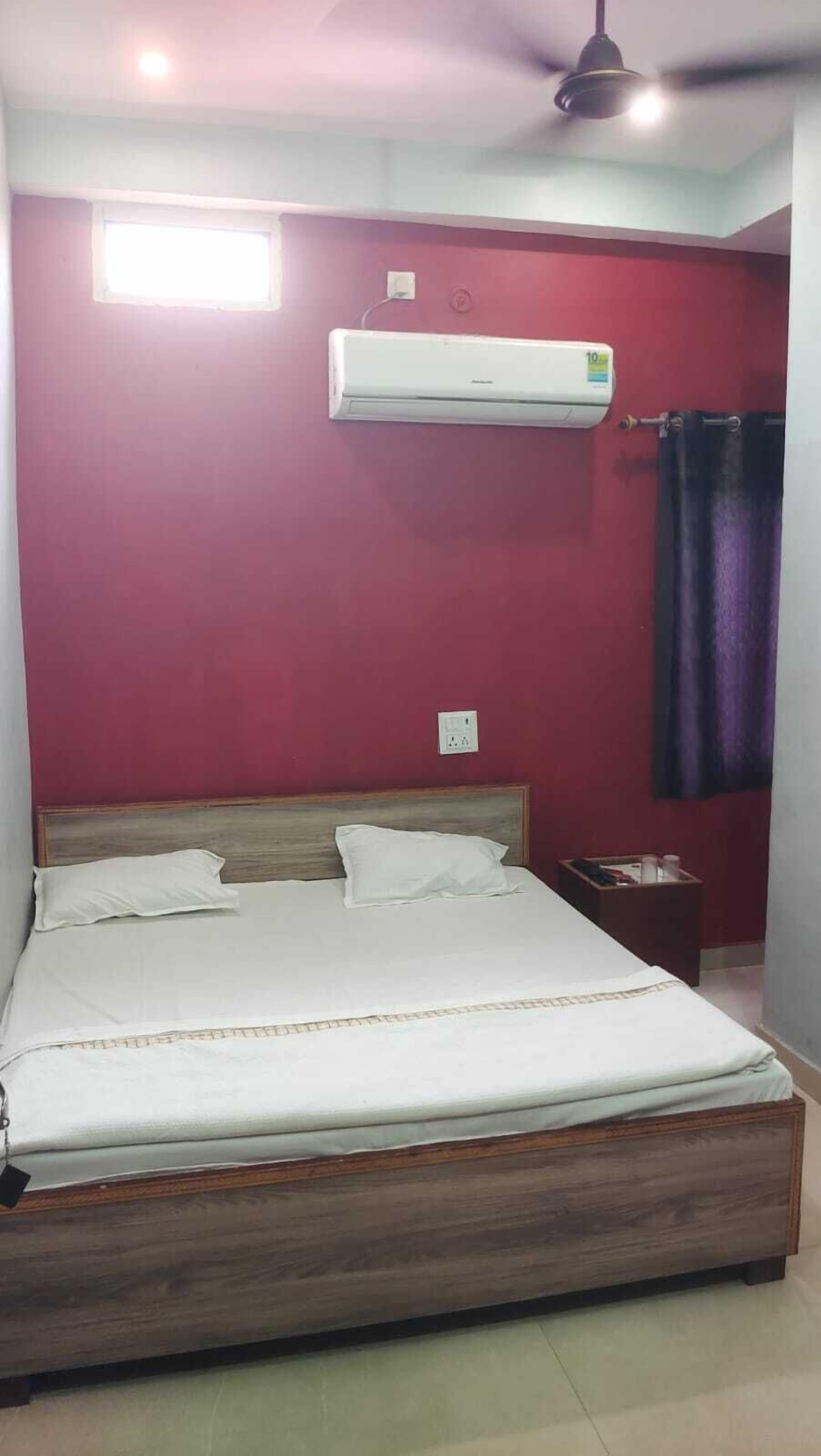 A bedroom with a wooden bed, an air conditioner, a nightstand, and a ceiling fan.