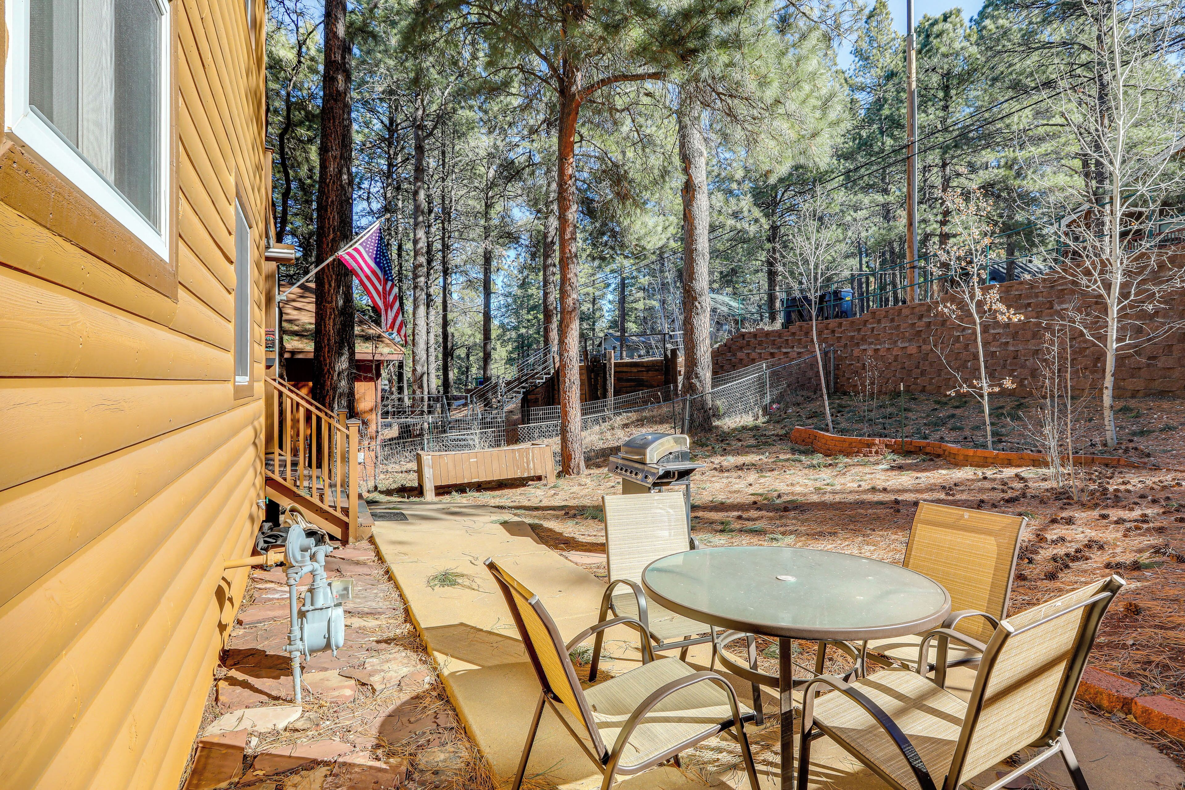 Una cabaña de madera con un patio que tiene muebles de exterior, una parrilla y una bandera.