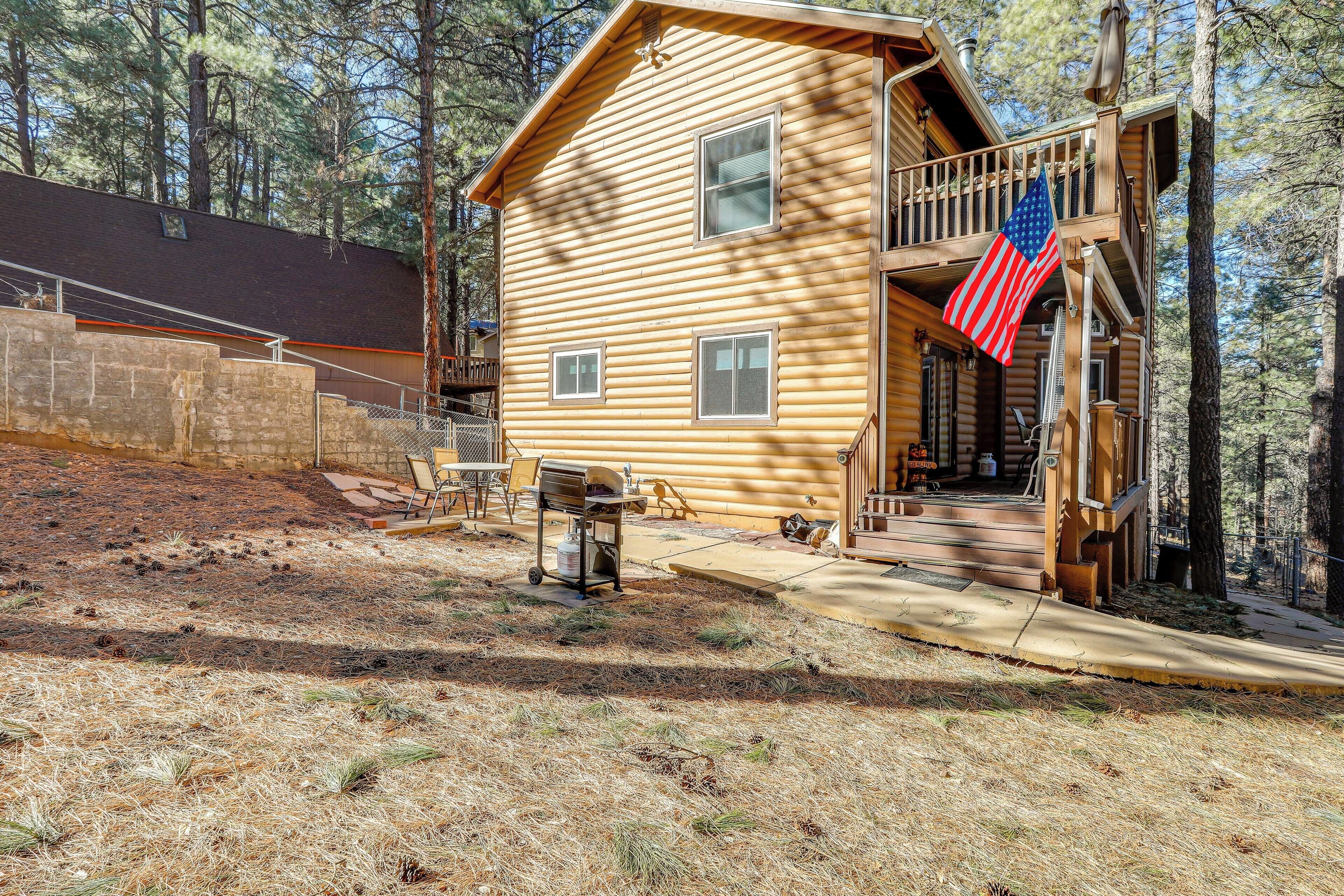 A wooden cabin with a balcony, a flag, and a grill outside.