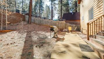 Une cabane en bois avec un patio en béton, entourée d’arbres.