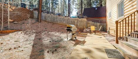 A wooden cabin with a concrete patio, surrounded by trees.