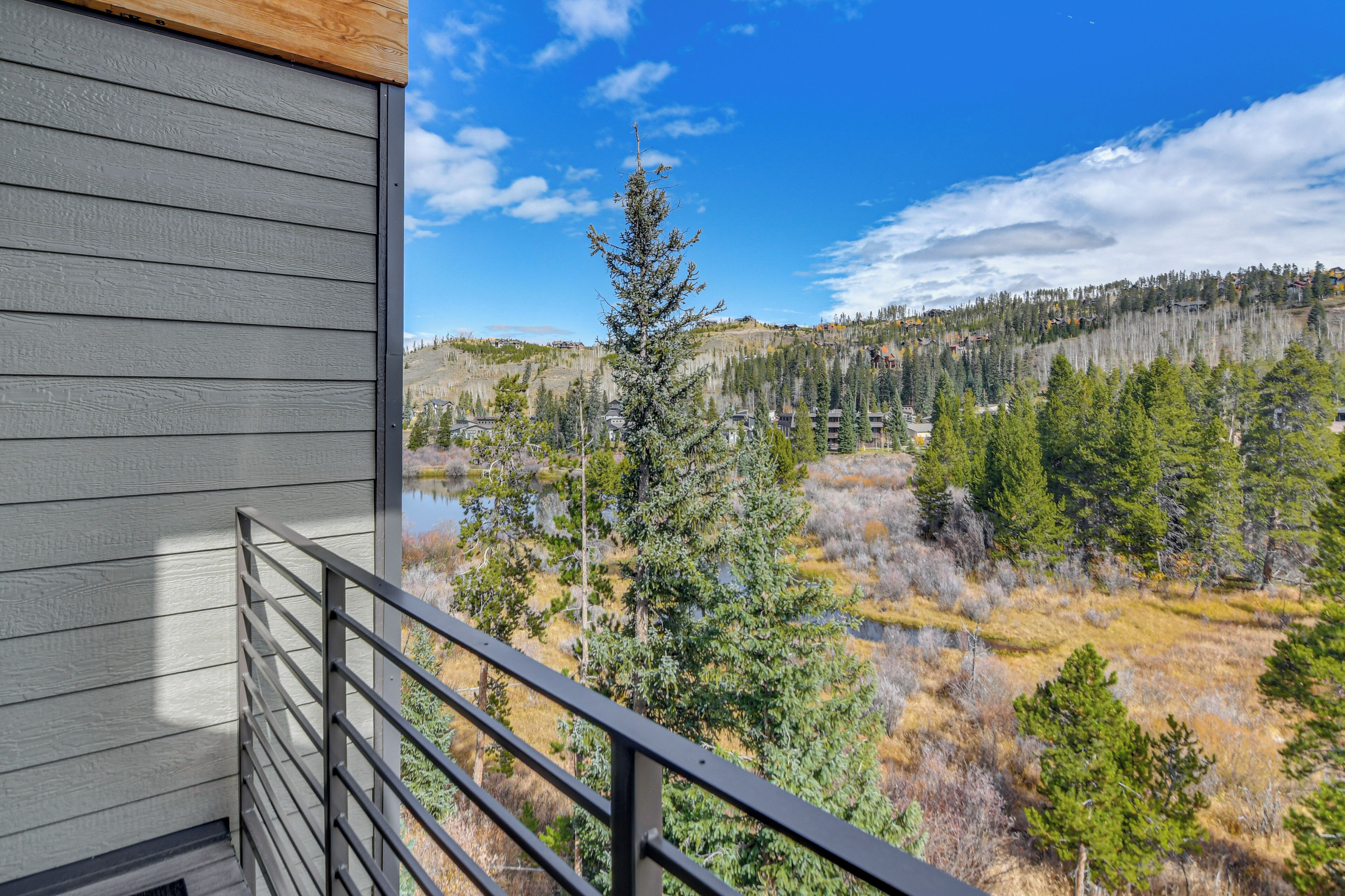 A balcony with a view of a forested area and a body of water.