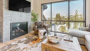 A modern living room with a fireplace, large windows, and a cozy seating area. - Near Hiking & Biking: Winter Park Mtn-view Haven! (Winter Park)