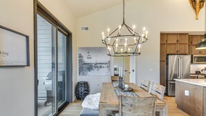 A modern kitchen with wooden cabinets, a stainless steel refrigerator, and a dining area with a wooden table and chairs. - Near Hiking & Biking: Winter Park Mtn-view Haven! (Winter Park)