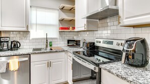 A modern kitchen with white cabinets, a granite countertop, a stove, an oven, a microwave, and a coffee maker. - 6 Mi to The Masters: Updated Home w/ Yard! (Augusta)
