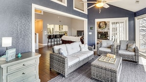 A living room with wicker furniture, a ceiling fan, and a view to the dining area. - Boat, Swim & Enjoy Lake Views: Osage Beach Retreat (Osage Beach)