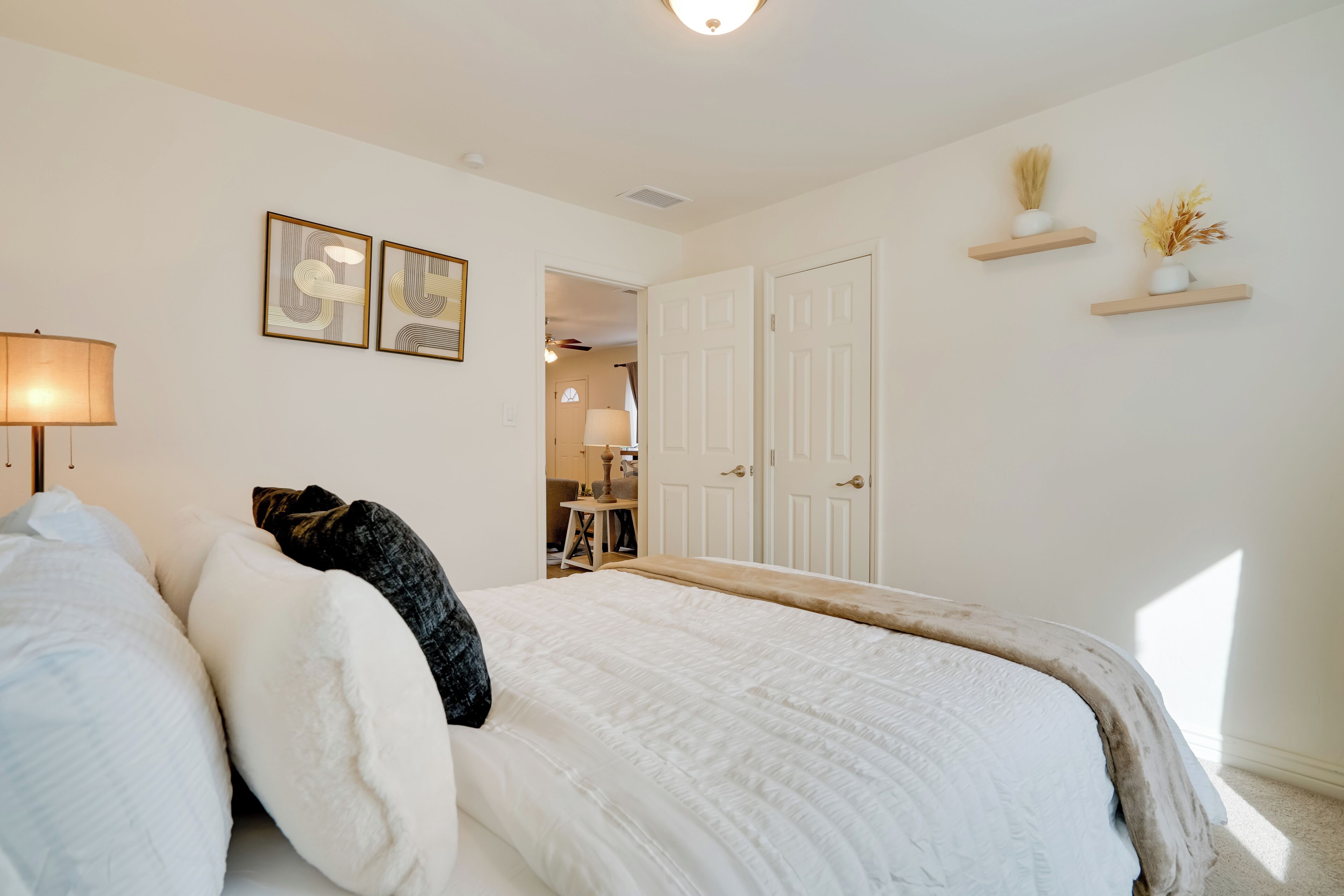 A bedroom with a bed, a nightstand, a lamp, and a door.