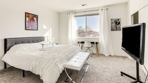 A modern bedroom with a large bed, a desk, a chair, a TV, and a window with curtains. - 4 Mi to Dtwn: Family-friendly Townhome in Reno (Reno)