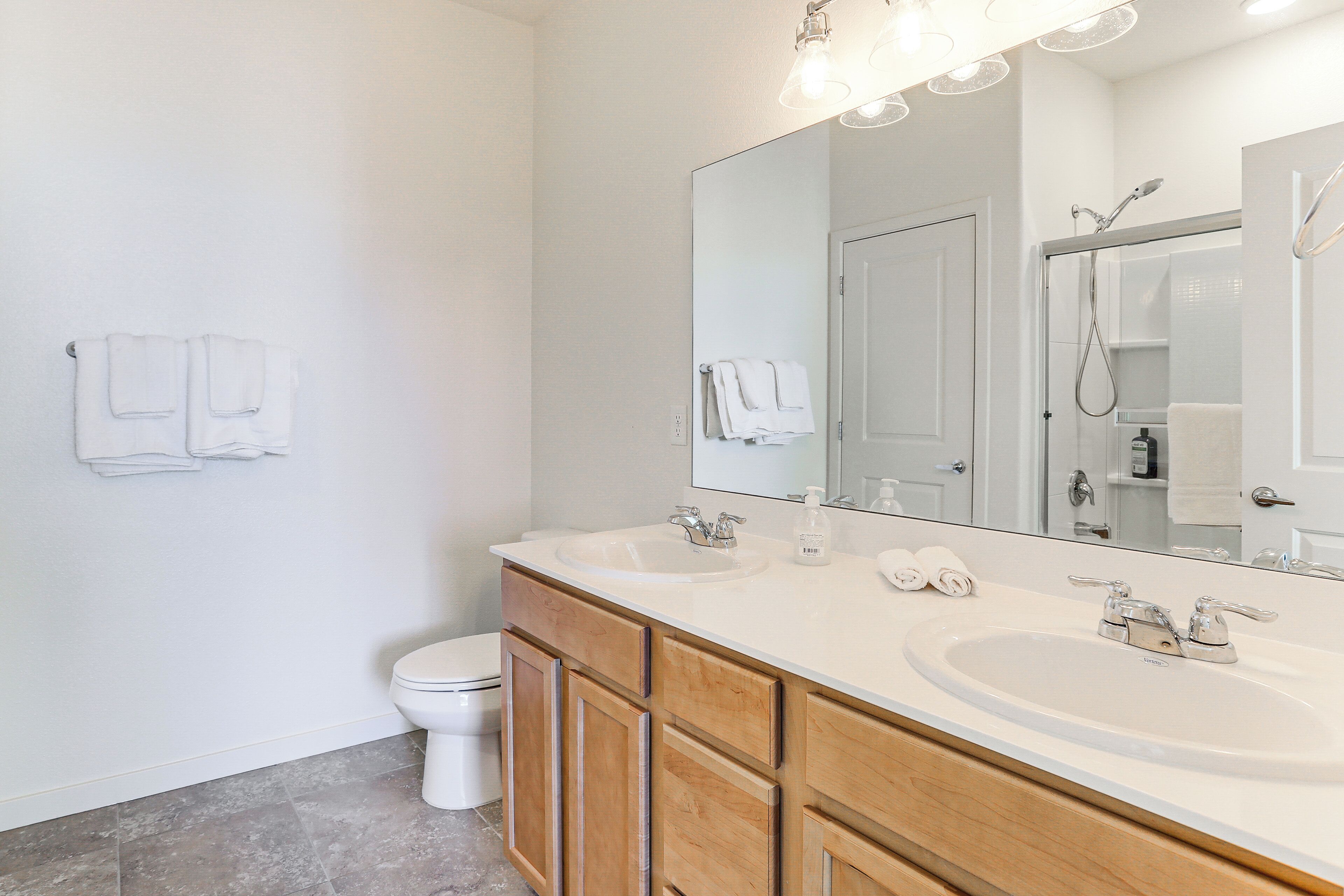 A bathroom with two sinks, a toilet, and a large mirror.
