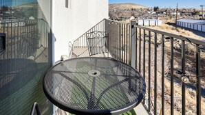 A balcony with a metal table and chairs, a white building in the background, and a view of a hilly landscape. - 4 Mi to Dtwn: Family-friendly Townhome in Reno (Reno)