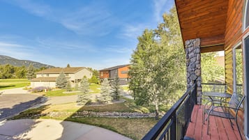 A residential property with a wooden deck, stone pillar, and a view of neighboring houses and a mountain.