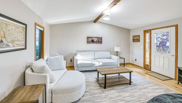 A spacious living room with a white sofa, a coffee table, and a wooden floor. There is a framed map on the wall and a door with a window. - 3 Mi to Dtwn: Mtn-view Red Lodge Retreat! (Red Lodge)