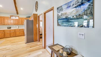 Una cocina con armarios de madera, un refrigerador y una zona de comedor con mesa y sillas.