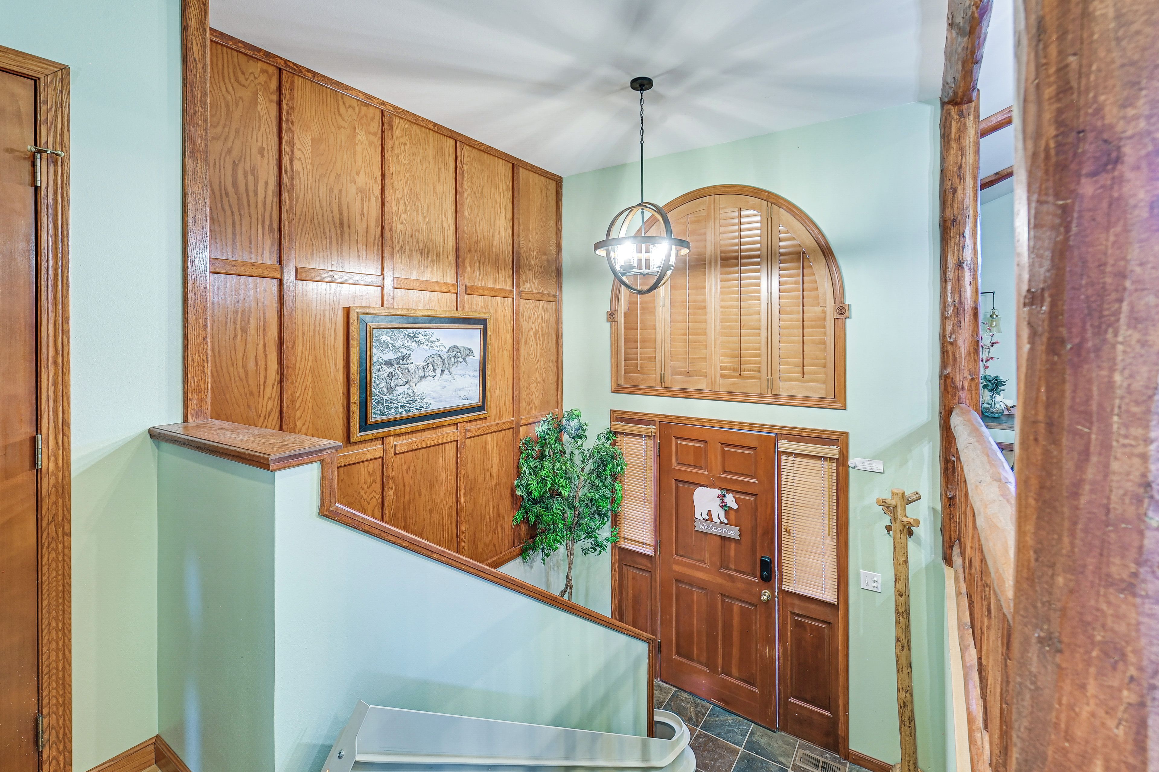 A wooden interior with a framed picture, a hanging light fixture, and a welcome sign.