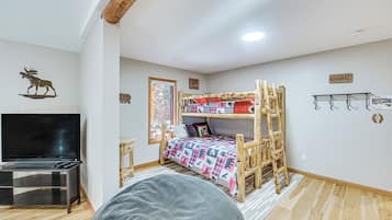 Una habitación con literas, una televisión y techo de madera.