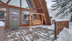 A wooden deck with a swing set, snow-covered ground, and a wooden fence. - Red Lodge Cabin w/ Hot Tub ~ 1/2 Mi to Downtown! (Red Lodge)