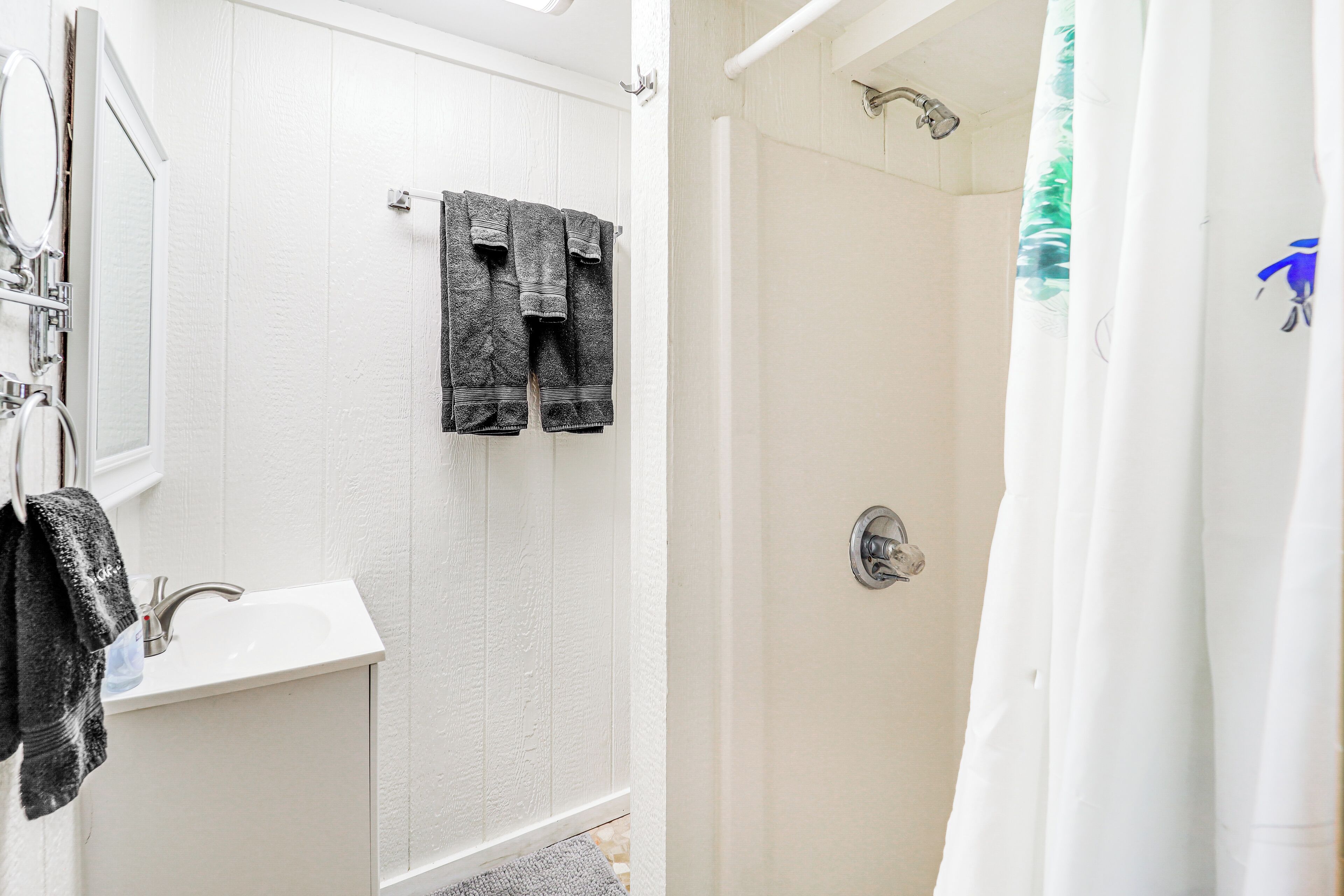 Une salle de bain avec un lavabo blanc, un miroir et deux serviettes accrochées au mur.