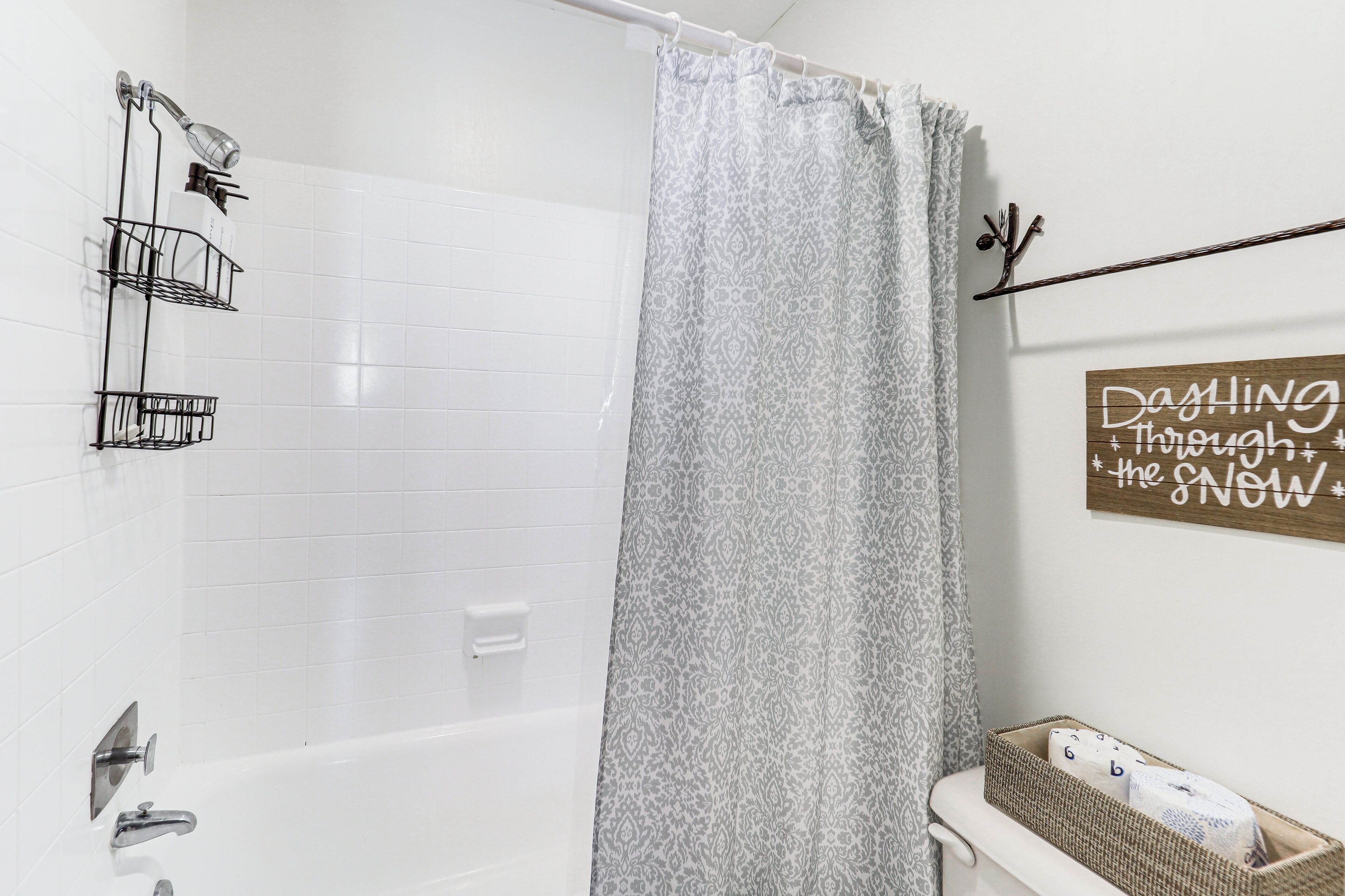 A bathroom with a white bathtub, a shower, a towel rack, and a decorative sign on the wall.
