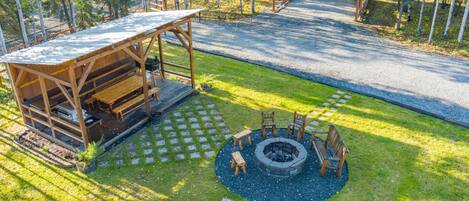 A wooden cabin with a deck, a fire pit, and a stone pathway.