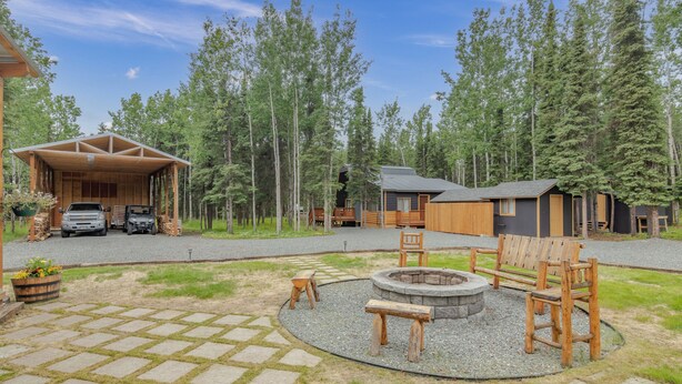 Een chalet met een overdekte veranda, een vuurplaats en zitplaatsen buiten.