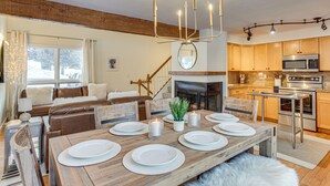 A modern kitchen with a built-in microwave, stove, and oven. There is a dining area with a wooden table set for four, and a cozy seating area with a fireplace. - Par & Powder: Avon Haven w/ Golf & Ski Access! (Avon)