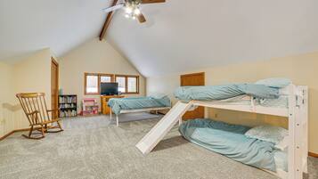 A bedroom with bunk beds, a ceiling fan, a bookshelf, and a window.