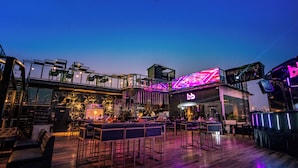 An outdoor bar area with seating and a neon sign. - THE COURTYARD - Beyond Bar & Club (Udaipur)