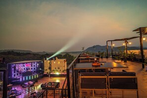 Eine Dachterrasse mit Bühne, Sitzgelegenheiten und Blumentöpfen.