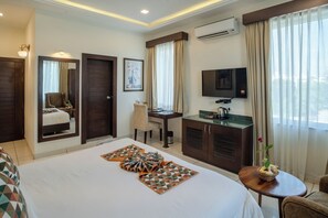 Ein Hotelzimmer mit Bett, Schreibtisch, Fernseher und Badezimmer.