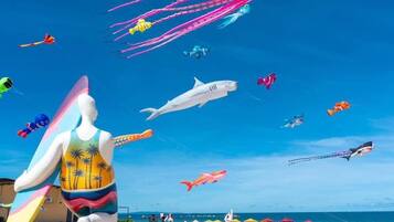 A beach with colorful kites, including octopus and shark shapes, and a lifeguard statue.