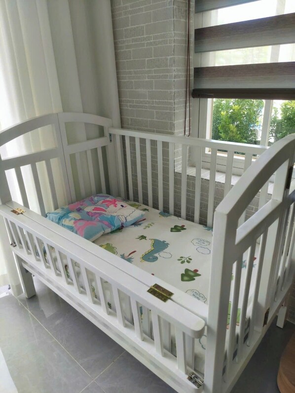 Un berceau blanc avec un matelas coloré et une vue sur la fenêtre.