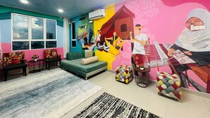 A colorful room with a mural, a sofa, a small table, and a chair.