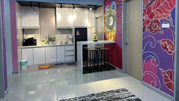 A modern kitchen with white cabinets, a black refrigerator, and a small island with stools.