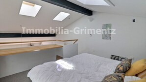 Une chambre à coucher moderne avec un lit en mezzanine, des fenêtres de toit et un design minimaliste.