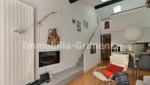 Un salon moderne doté d’un téléviseur à écran plat, d’un canapé recouvert d’un plaid et d’un escalier menant à un niveau supérieur.