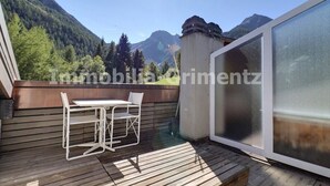 Un balcon avec une table et des chaises, donnant sur un paysage montagneux.