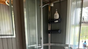 Un baño moderno con ducha envuelta en vidrio, un lavabo blanco y un inodoro.