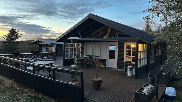 Una cabaña con terraza, asientos al aire libre y televisor.