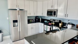 A modern kitchen with white cabinets, stainless steel appliances, and a central island with seating.