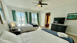 A hotel room with two beds, a TV, a dresser, and a painting on the wall.