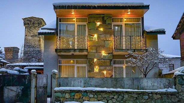 Un edificio de varios pisos con paredes de piedra y balcones decorados con luces colgantes.