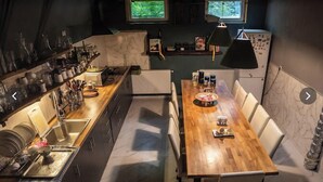 Una cocina compacta con una mesa de comedor de madera, electrodomésticos integrados y vistas a la vegetación por las ventanas.