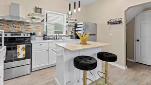 A modern kitchen with white cabinetry, a stainless steel range, and a central island with black stools. - Cozy 1-bedroom with AC and WiFi in lovely Elizabeth (Elizabeth)