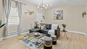 A modern living room with a sectional sofa, a coffee table, and a small side table with a plant. - Cozy 1-bedroom with AC and WiFi in lovely Elizabeth (Elizabeth)