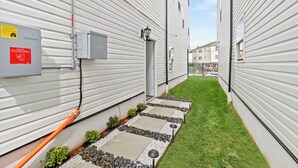 A narrow pathway flanked by white buildings with solar panels and a warning sign. - Cozy 1-bedroom with AC and WiFi in lovely Elizabeth (Elizabeth)