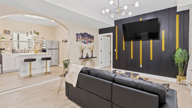A modern kitchen with a central island, a black leather sofa, and a flat-screen TV mounted on the wall. - Cozy 1-bedroom with AC and WiFi in lovely Elizabeth (Elizabeth)
