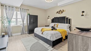 A modern bedroom with a bed, bedside tables, a desk, and a large window with curtains. - Cozy 1-bedroom with AC and WiFi in lovely Elizabeth (Elizabeth)
