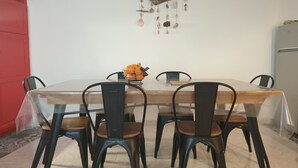 A dining area with a rectangular table, black chairs, and a decorative wall hanging above. - Village house close to the lagoon and the sea (Marseillan)