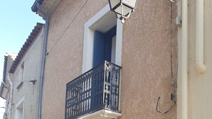 A two-story building with a balcony, a door, and a small plant on the ground floor. - Village house close to the lagoon and the sea (Marseillan)
